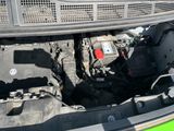 a green car with its hood open and the engine in the trunk