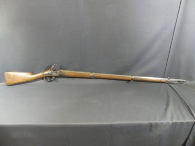 an old rifle is sitting on a table with a gray cloth