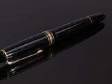 black and gold fountain pen on a black surface with reflection