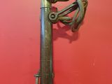 an old gun hanging on a red wall with a red wall in the background
