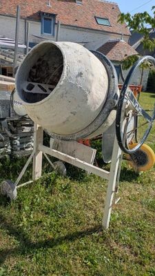 a cement mixer sitting on the grass in front of a house