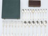 an assortment of silverware including forks, spoons, and a book