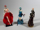 three figurines of women dressed in different styles of clothing