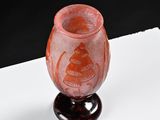 a red vase with a monkey on it on a table
