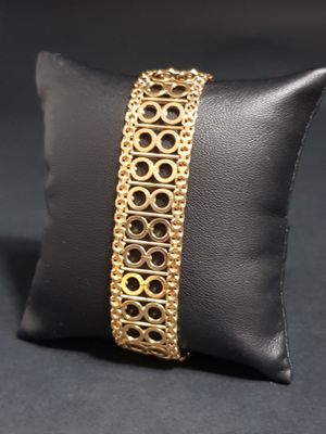 a close up of a gold bracelet on a pillow on a black surface