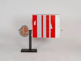 a red and white sign on a stand with a fan
