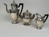 three pieces of silver tea and coffee set on a white surface