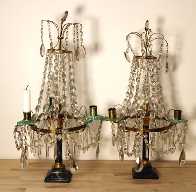 une paire de chandeliers anciens en laiton et cristal posés sur une table en bois