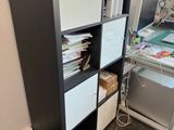 a black and white bookcase next to a desk with a computer on it