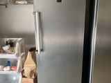 un réfrigérateur en acier inoxydable dans une cuisine au sol carrelé de blanc