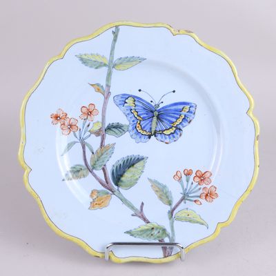 une assiette bleue et jaune sur laquelle est représenté un papillon