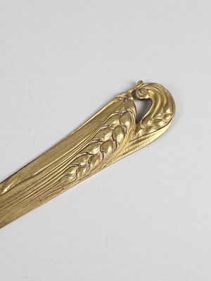 une cuillère en or ornée d'un motif sur un fond blanc
