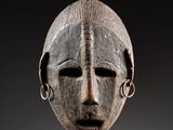 une image d'un masque en bois sur fond noir