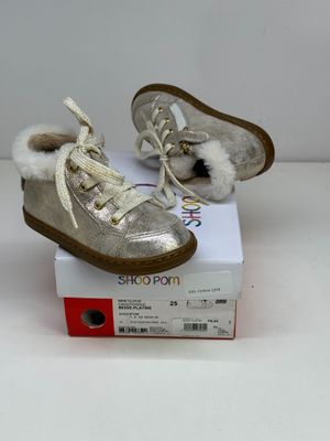 une paire de chaussures de bébé doublées de fourrure, posée sur une boîte