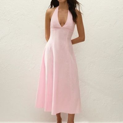 une femme en robe rose posant pour une photo devant un mur blanc