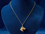 a gold necklace with a dog ' s head on a mannequin