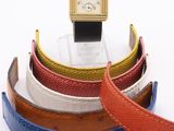 a watch sitting on top of a stack of different colored belts