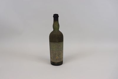 une vieille bouteille d'alcool posée sur une surface blanche