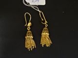 une paire de boucles d'oreilles en or ornées de pompons sur un fond noir