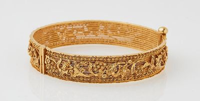 a close up of a gold bracelet on a white surface