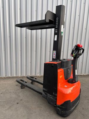 un chariot élévateur orange et noir garé devant un immeuble