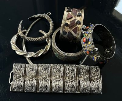 a lot of silver jewelry on a black table