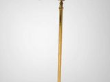 a gold floor lamp with a white shade on top of it
