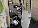 a small white truck with a door open on the side of the road