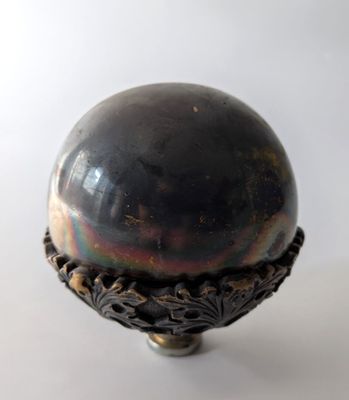 une boule métallique posée sur un socle, sur une surface blanche