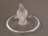 a glass bird sitting on a glass plate on a table