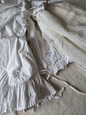 a white dress laying on top of a bed next to a pair of shoes