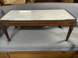une table basse au plateau en marbre posée devant un canapé bleu