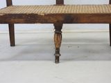 a wooden bench with a wicker seat on top of it