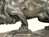bronze statue of a lion on a rock on a white background