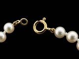 a close up of a white pearl bracelet with a gold clasp