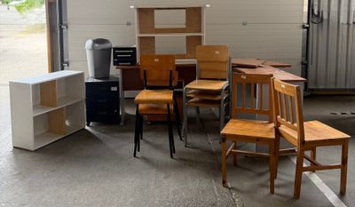 de nombreuses chaises et bureaux en bois dans un garage