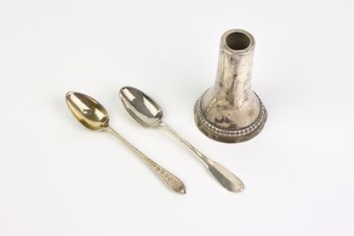 two silver spoons and a silver cup on a table