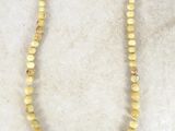 a close up of a yellow beaded necklace on a white surface