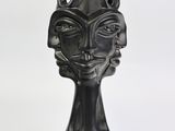 sculpture noire représentant le visage d'une femme avec des cornes, sur fond blanc