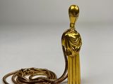 une figurine en or entourée d'une chaîne, posée sur une surface blanche
