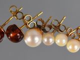 four pairs of pearl and gold earrings on a gray background