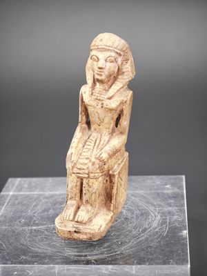 une statue égyptienne antique représentant une femme assise sur un rocher