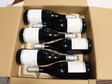 six bottles of wine in a cardboard box on a table