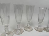 six empty wine glasses lined up on a white surface