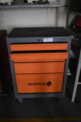 une boîte à outils orange posée sur un chariot métallique dans un garage