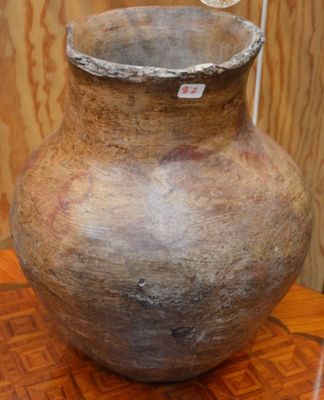 un grand vase posé sur une table en bois, sur laquelle est accrochée une étiquette