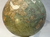 a green globe on a black stand on a white background