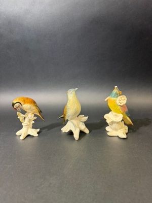 three figurines of birds sitting on top of a table next to each other