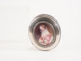 un médaillon ovale en argent orné du portrait d'une femme vêtue d'une robe rose