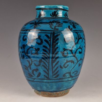 un vase bleu orné de motifs noirs sur un fond blanc